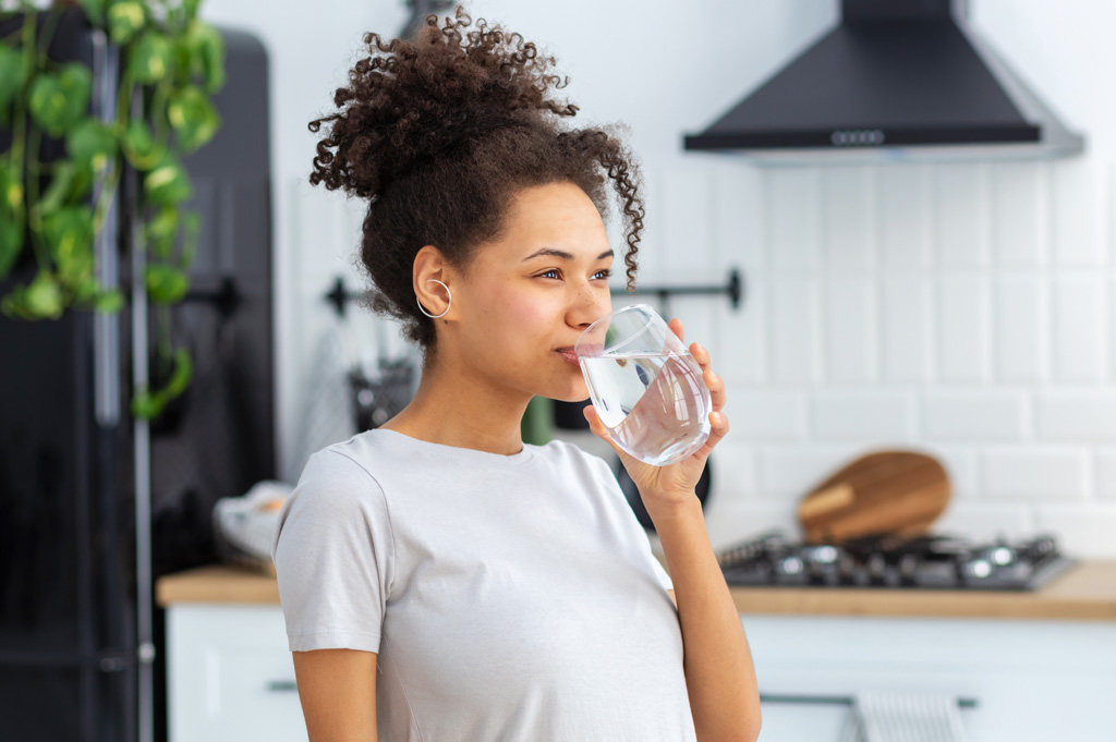 woman drinking water in kitchen